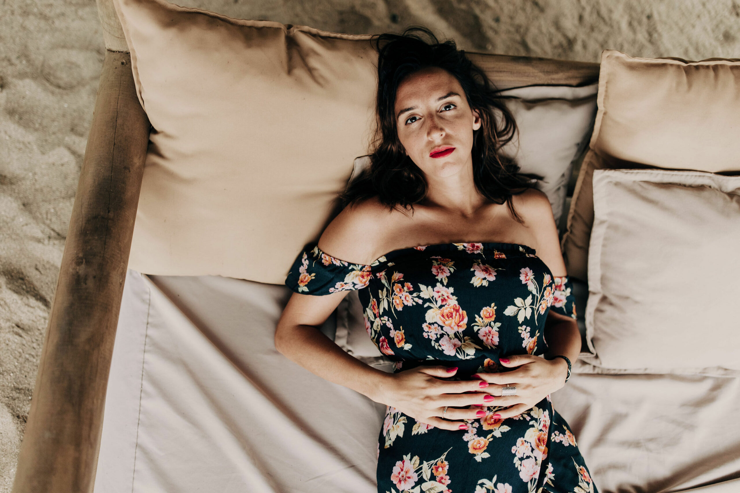 Photo of a woman laying on a bed in a black flowery dress